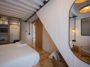 a bedroom with a bed and a mirror at GuestReady - ALMA - Island House in Faial da Terra