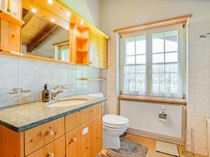 a bathroom with a toilet and a sink and a window at Sonniges Chalet mit fantastischem Bergblick in Lenk