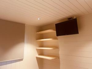 a room with wooden shelves and a tv on the wall at Natuur, Rust & Ontspanning in de Ardennen in Rendeux