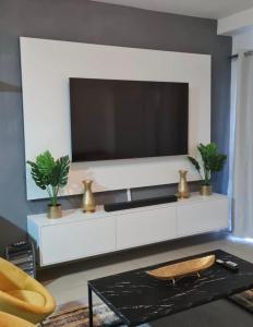 a living room with a large television on a white cabinet at Modern 2 Bed 1 Bath Apt With Complex Pool in Johannesburg