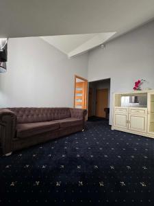 a living room with a brown couch and a cabinet at Hotel Jan in Zgorzelec