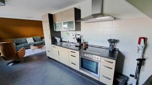 a kitchen with a stove top oven next to a couch at Nordmannsland I in Sudermarsch