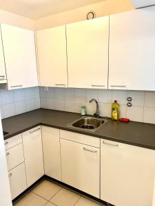a kitchen with white cabinets and a sink at Downtown Flats - Lake Lucerne in Lucerne