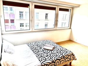 a bed in a room with two windows at Downtown Flats - Lake Lucerne in Lucerne +10 photos