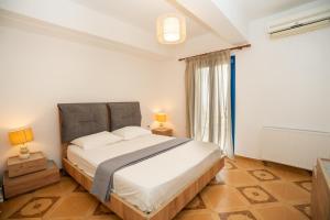 a bedroom with a large white bed and a window at Blue Veranda Apartment in Pera Gyalos