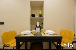 a dining room table with two yellow chairs and a table with plates at City center 4’|Studio|wifi|By tilo in Genoa +13 photos