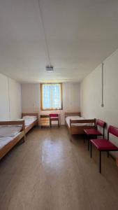 a large room with two beds and chairs and a window at Wellness & Nature Hostel in Pirkenhammer +24 photos