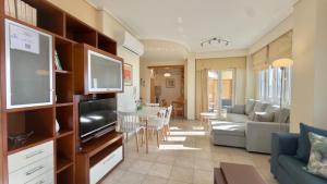 a living room with a couch and a tv and a table at Lumaverde Estate in Kalamata