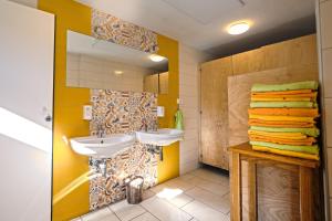 a bathroom with yellow walls and two sinks and towels at Glamping by the Old Mill in Preddvor