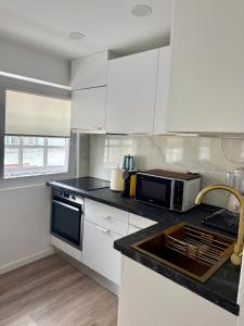 a kitchen with white cabinets and a black counter top at O Refúgio dos Ferreiros in Guarda