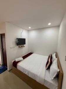a bedroom with a bed with a tv on the wall at Aero Inn in Nedumbassery