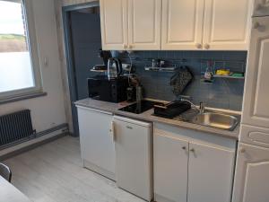 a kitchen with white cabinets and a sink at Cambuse Appartement à Sangatte au premier étage à 50 metres de la plage in Sangatte