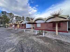 a row of houses with straw umbrellas at Hotel El Colonial in San Antonio Oeste