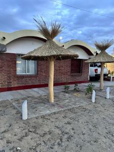 two large straw umbrellas in front of a building at Hotel El Colonial in San Antonio Oeste +5 photos