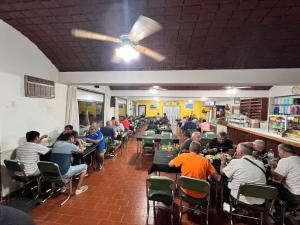 a group of people sitting at tables in a restaurant at Hotel El Colonial in San Antonio Oeste