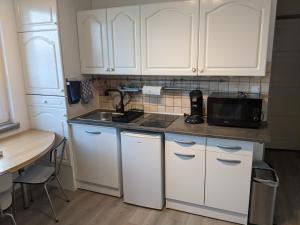 a kitchen with white cabinets and a sink and a microwave at Mousse appart 3 pers à Sangatte au 1e étage à 50 metres de la plage in Sangatte