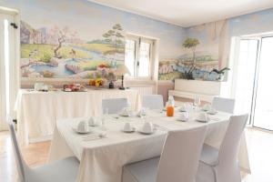 a dining room with a table with white chairs and a mural at La Casa di Mimma in Caposele