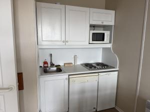 a small kitchen with white cabinets and a microwave at Les balcons de Valmi vue montagne Piscine in Valmeinier