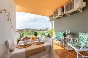 a dining room with a table and chairs and a balcony at Apto Oasis Playa & Golf Almerimar in Almerimar