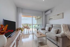a living room with a couch and a tv at Apto Oasis Playa & Golf Almerimar in Almerimar