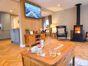 a living room with a table with glasses and a fireplace at Kestrel Lodge - hot tub , sauna, EV and bike storage in Aviemore