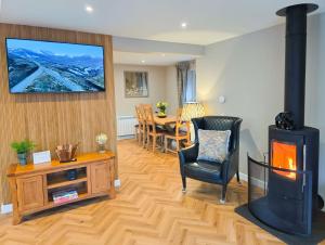 a living room with a fireplace and a dining room at Kestrel Lodge - hot tub , sauna, EV and bike storage in Aviemore