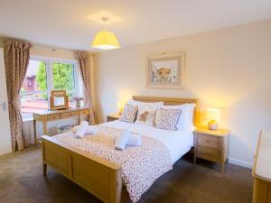 a bedroom with a large bed and a window at Kestrel Lodge - hot tub , sauna, EV and bike storage in Aviemore