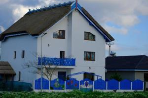 a white house with a blue fence in front of it at Casa cu flori in Tulcea