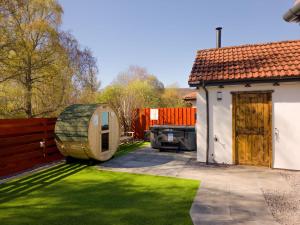 a garden with a water barrel next to a house at Kestrel Lodge - hot tub , sauna, EV and bike storage in Aviemore