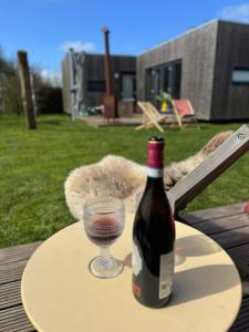 a bottle of wine and a glass on a table at Sinne - Ecohuisjes Terschelling in Midsland +16 photos