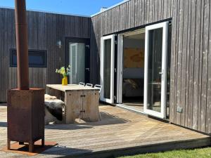 a wooden deck with a table and a building at Sinne - Ecohuisjes Terschelling in Midsland