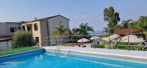 a swimming pool with umbrellas and a house at B&b Le paradis in Castel di Tusa