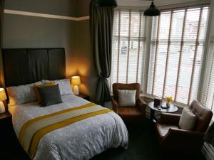 a bedroom with a bed and a chair and windows at Dewsbury House in Blackpool