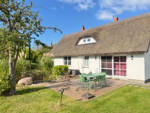 a cottage with a table and chairs in the yard at Reetferienhaus - Schaprode Hafen in Schaprode