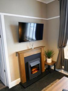 a living room with a fireplace with a tv above it at Dewsbury House in Blackpool