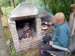 a man cooking food in a brick oven at Etno Han crvena reka in Bela Palanka