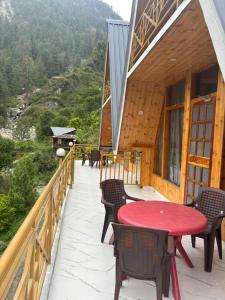 a deck with a red table and chairs on a house at Clifton Chapter Cottage Tirthan in Banjār