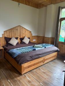 a bedroom with a large bed with a wooden headboard at Clifton Chapter Cottage Tirthan in Banjār