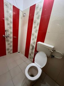 a bathroom with a toilet with red and white walls at Himora in Gupta Kāshi
