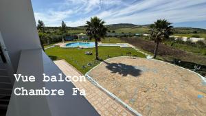 a view of a swimming pool and palm trees at GUITAR PALACE - Chambres d'hôtes in Bni Quolla