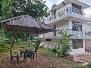 a table with chairs and an umbrella in front of a building at G4 homez in Morogoro