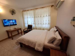 a bedroom with a bed and a tv and a window at G4 homez in Morogoro