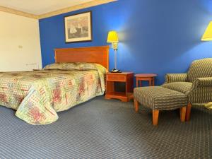 a hotel room with a bed and a chair at Wethersfield Motel in Wethersfield