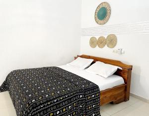 a bedroom with a bed with a black and white blanket at Hôtel villa blanca in Lomé +12 photos