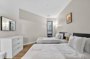 a white bedroom with two beds and a dresser at Spacious & Modern 2BR 2BA unit in assembly square in Somerville