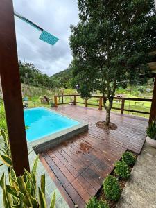 a wooden deck with a swimming pool and a tree at Rancho Nosso Lago in Domingos Martins