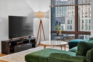 a living room with a green couch and a flat screen tv at Spacious & Modern 2BR 2BA unit in assembly square in Somerville