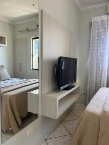 a bedroom with a bed and a tv in a cabinet at Apto no Centro de Guaíra com ar condicionado na sala e quarto in Guaíra
