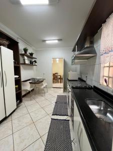 a large kitchen with a sink and a table at Apto no Centro de Guaíra com ar condicionado na sala e quarto in Guaíra +62 photos