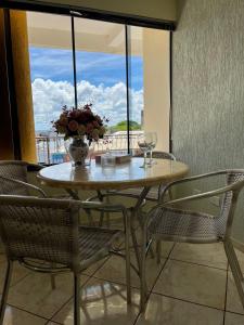 a table with chairs and a vase of flowers on it at Apto no Centro de Guaíra com ar condicionado na sala e quarto in Guaíra